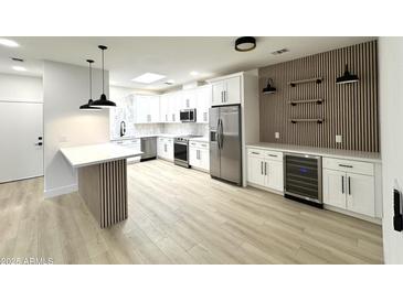 Bright kitchen features stainless steel appliances, island with seating and wood panel accent wall with shelving at 3221 N 37Th St # 26, Phoenix, AZ 85018