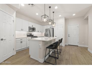 Well-lit modern kitchen boasts white cabinetry, stainless steel appliances, and a quartz countertop island with seating at 8343 E Irwin Ave, Mesa, AZ 85209