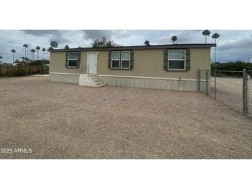 Tan home featuring three windows and a front entrance with a gravel lot at 10231 E Illini St, Mesa, AZ 85208