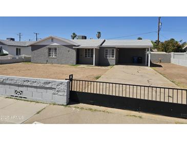 Charming gray home featuring a covered carport, black iron gate, and a low-maintenance yard at 1630 E Catalina Dr, Phoenix, AZ 85016