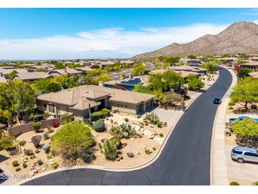 A beautiful aerial view of a desert home with lush landscaping and mountain views in the distance at 16562 N 109Th Way, Scottsdale, AZ 85255