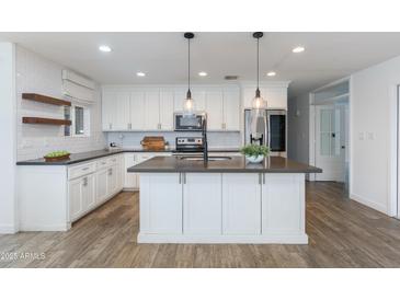 Bright kitchen with white cabinetry, stainless steel appliances, and an island with pendant lighting at 1820 W Seldon Way, Phoenix, AZ 85021