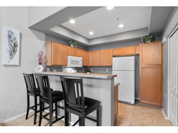 Modern kitchen with wood cabinets, stainless steel appliances, and breakfast bar seating at 2201 N Comanche Dr # 1094, Chandler, AZ 85224