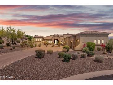 Desert landscaping surrounds this luxury home with an arched entryway and tile roof at 3217 N Piedra Cir, Mesa, AZ 85207