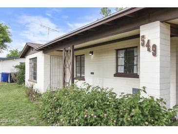 Charming home's exterior with a well-maintained lawn and blooming flower bushes at 549 N Olive --, Mesa, AZ 85203