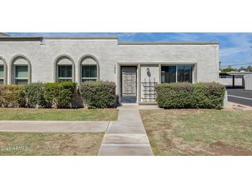 Charming single-story stucco home featuring arched windows and lush landscaping enhancing curb appeal at 5809 E Thomas Rd, Scottsdale, AZ 85251