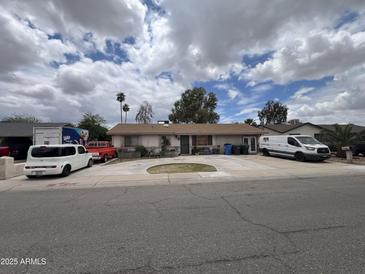 Charming single-story home with mature trees, green lawn, spacious driveway, and various vehicles parked in front at 6823 W Garfield St, Phoenix, AZ 85043