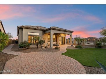 Beautiful backyard featuring a covered patio, green lawn, and mature landscaping at sunset at 8234 E Inca St, Mesa, AZ 85207