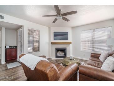 Inviting living room with a cozy fireplace, modern ceiling fan, and comfortable leather seating at 8787 E Mountain View Rd # 2008, Scottsdale, AZ 85258