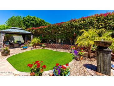 Beautiful backyard featuring a gazebo, manicured landscaping, and vibrant flowers at 1361 N Claiborne --, Mesa, AZ 85205