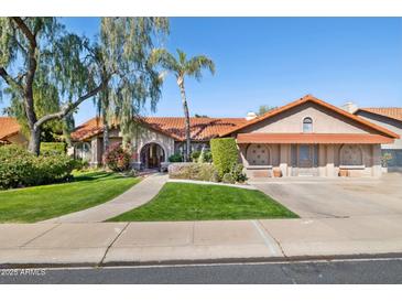 Charming single-story home with a red tile roof, arched entry, lush green lawn, and mature landscaping at 17030 N 57Th St, Scottsdale, AZ 85254