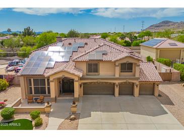 Elegant two-story home with tile roof, solar panels, three-car garage, and inviting front porch with seating at 24916 N 80Th Ln, Peoria, AZ 85383