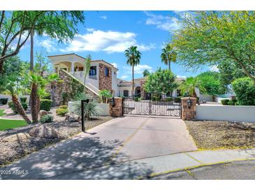 Stunning two-story home featuring stone accents, a tile roof, and a gated driveway entrance at 2527 E Beechnut Ct, Chandler, AZ 85249