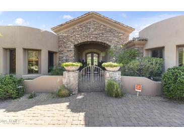 Elegant stone archway and gated entry enhance the curb appeal of this beautiful desert home at 13249 E Summit Dr, Scottsdale, AZ 85259
