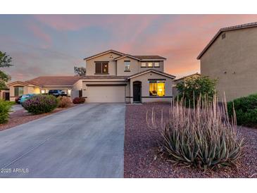 Two-story home featuring neutral tones, an attached two-car garage, and a well-maintained front yard at dusk at 1647 W Gold Mine Way, San Tan Valley, AZ 85144