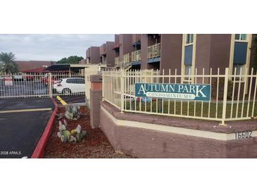 View of the Autumn Park Condominium sign and community buildings behind a fence with a vehicle parked nearby at 16602 N 25Th St # 123, Phoenix, AZ 85032