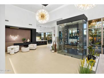 Bright living room with a glass-enclosed wine cellar, contemporary decor, and a view to the kitchen at 28754 N 107Th St, Scottsdale, AZ 85262