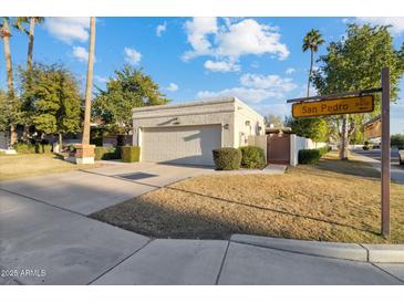 Beige home with a two-car garage and lush landscaping, complete with a beautiful lawn at 8405 E San Pedro Dr, Scottsdale, AZ 85258