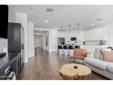 Open-concept living space showcasing hardwood floors, a kitchen with bar seating, and stylish furnishings at 14549 W Corrine Dr, Surprise, AZ 85379