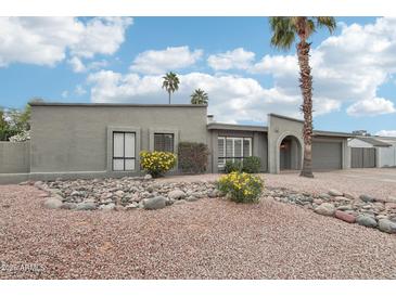 Charming single-story home with desert landscaping, mature palm trees, and neutral-colored exterior at 5119 E Shaw Butte Dr, Scottsdale, AZ 85254