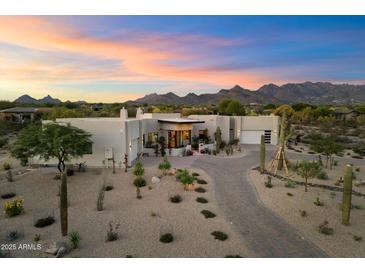Expansive desert home with neutral tones, desert landscaping, and mountain views at sunset at 9022 E Diamond Rim Dr, Scottsdale, AZ 85255