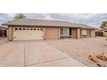 Charming single-story home features a brick exterior and a two-car garage and neutral gravel landscaping at 2502 S Mollera Cir, Mesa, AZ 85210