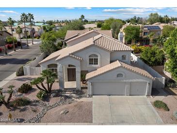 Two-story home showcasing a three-car garage and a well-maintained desert-style front yard with decorative rock landscaping at 5402 E Helena Dr, Scottsdale, AZ 85254