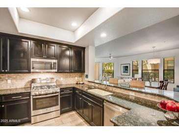 Modern kitchen featuring stainless steel appliances, granite countertops, and dark wood cabinetry at 7601 E Indian Bend Rd # 1050, Scottsdale, AZ 85250