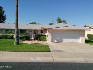 Charming single-story home with a two-car garage, complemented by a well-manicured lawn and mature landscaping at 10229 W Bolivar Dr, Sun City, AZ 85351