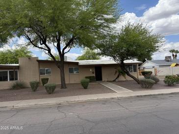Single-story home with mature trees and a desert-landscaped front yard at 1802 W Frier Dr, Phoenix, AZ 85021