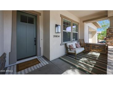 Inviting front porch features stylish decor, neutral stucco, stacked stone accents, and a welcoming entrance at 20834 W Prospector Way, Buckeye, AZ 85396