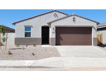 Charming single-story home featuring a brown two car garage and low maintenance desert landscaping at 37139 W Prado St, Maricopa, AZ 85138