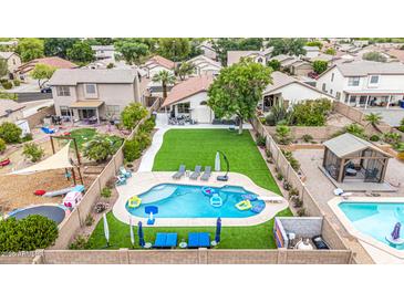 Aerial view of a landscaped backyard, featuring a pool, artificial grass, an outdoor kitchen, and a playground at 528 E Kyle Ct, Gilbert, AZ 85296