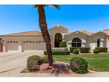 Charming home showcasing a manicured lawn, lush landscaping, and a three-car garage at 7648 W Mauna Loa Ln, Peoria, AZ 85381