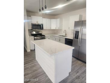 Modern kitchen with white cabinets, stainless steel appliances, island, and stylish lighting at 138 E Monte Way, Phoenix, AZ 85042