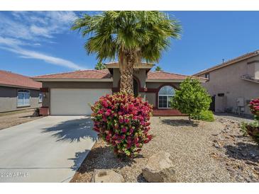 Charming home featuring desert landscaping, a blooming bush, and a tall palm tree in the front yard at 15848 W Calavar Rd, Surprise, AZ 85379