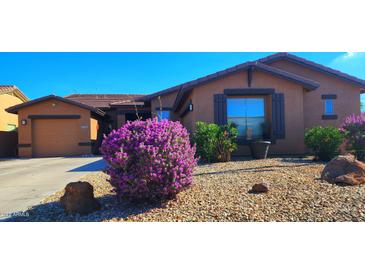 Charming single-story home with a well-maintained landscape featuring flowering shrubs and desert rock accents at 18177 W Tasha Dr, Surprise, AZ 85388