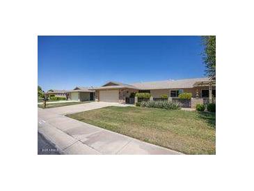 Charming single-story home with a well-manicured lawn, attached garage, and inviting curb appeal on a sunny day at 19018 N Concho Cir, Sun City, AZ 85373