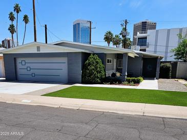 Charming single-story home boasts a well-manicured lawn, gray exterior, and a convenient attached garage in a sunny neighborhood at 3137 N 4Th Ave, Phoenix, AZ 85013