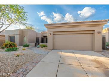 Beige home featuring desert landscaping and a two car garage at 6996 E Mighty Saguaro Way, Scottsdale, AZ 85266