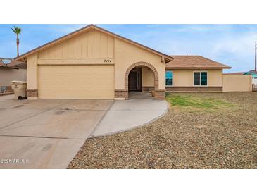 Charming single-story home featuring a tan exterior, an arched entryway, and a two-car garage at 7114 W Oregon Ave, Glendale, AZ 85303
