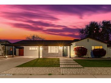 Charming home featuring a covered carport, a well-kept lawn and a beautiful pink and purple sunset at 7308 E Diamond St, Scottsdale, AZ 85257