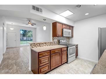 Well-lit kitchen featuring tile backsplash, stainless steel appliances, and updated cabinets at 13424 N Emberwood Dr, Sun City, AZ 85351