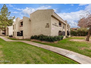 Low angle view of exterior with nice landscaping, and green lawns and a sidewalk leading to the building at 3119 W Cochise Dr # 111, Phoenix, AZ 85051