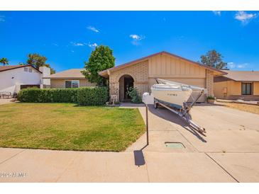 Charming single-story home with well-manicured lawn, desert landscaping, and boat parked in the driveway at 3237 W Angela Dr, Phoenix, AZ 85053