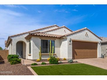 Charming home featuring a well-manicured lawn, desert landscaping, and a tile roof at 9570 W Whispering Wind Dr, Peoria, AZ 85383