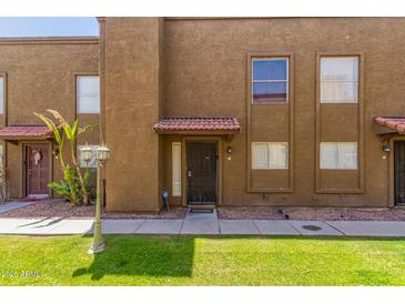 Inviting townhouse exterior features a red tile roof, secure front door, and manicured lawn at 16225 N 30Th St # 11, Phoenix, AZ 85032
