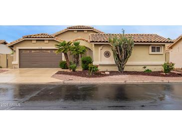 Charming single-story home featuring a tile roof, desert landscaping, and a two-car garage at 17718 N Desert Flower Trl, Surprise, AZ 85374