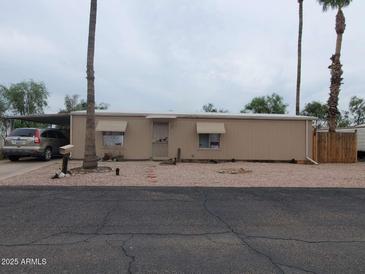 Tan single-story home with gravel yard and covered parking area showcasing a tidy and low-maintenance front at 200 E Ivanhoe St, Chandler, AZ 85225