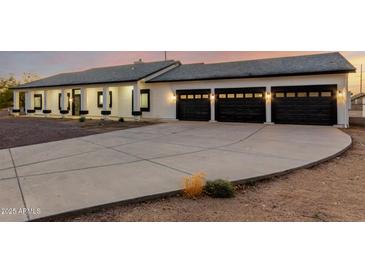 Modern home boasting a three-car garage and a well-lit driveway at dusk at 25450 W Pueblo Ave, Buckeye, AZ 85326